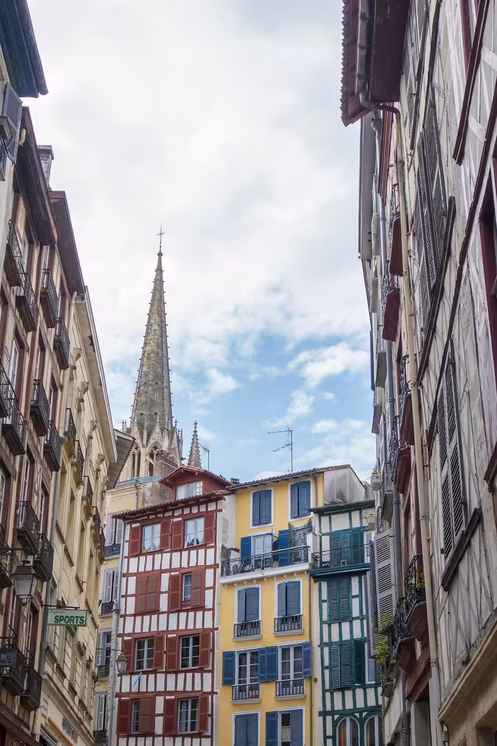 Les maisons à colombages colorées du vieux Bayonne le long de la rue, la flèche de la cathédrale au fond