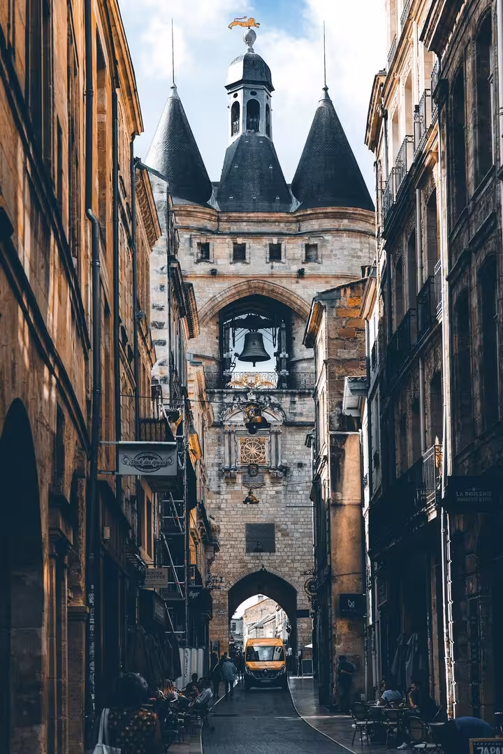 La Grosse Cloche de Bordeaux vue depuis une rue étroite du vieux centre, entre les façades de pierre et les terrasses