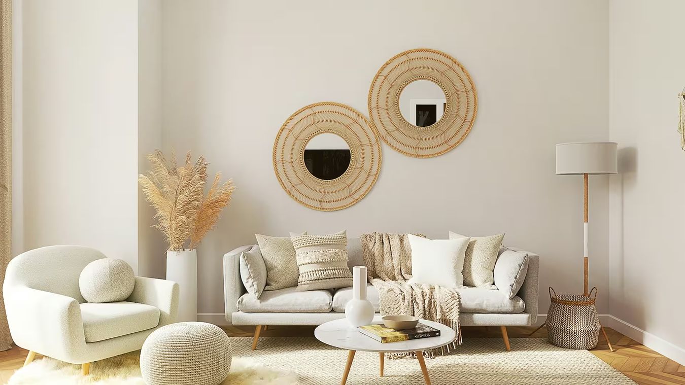 Un salon aux tons naturels : canapé blanc, fauteuil bouclé, miroirs en rotin et tapis