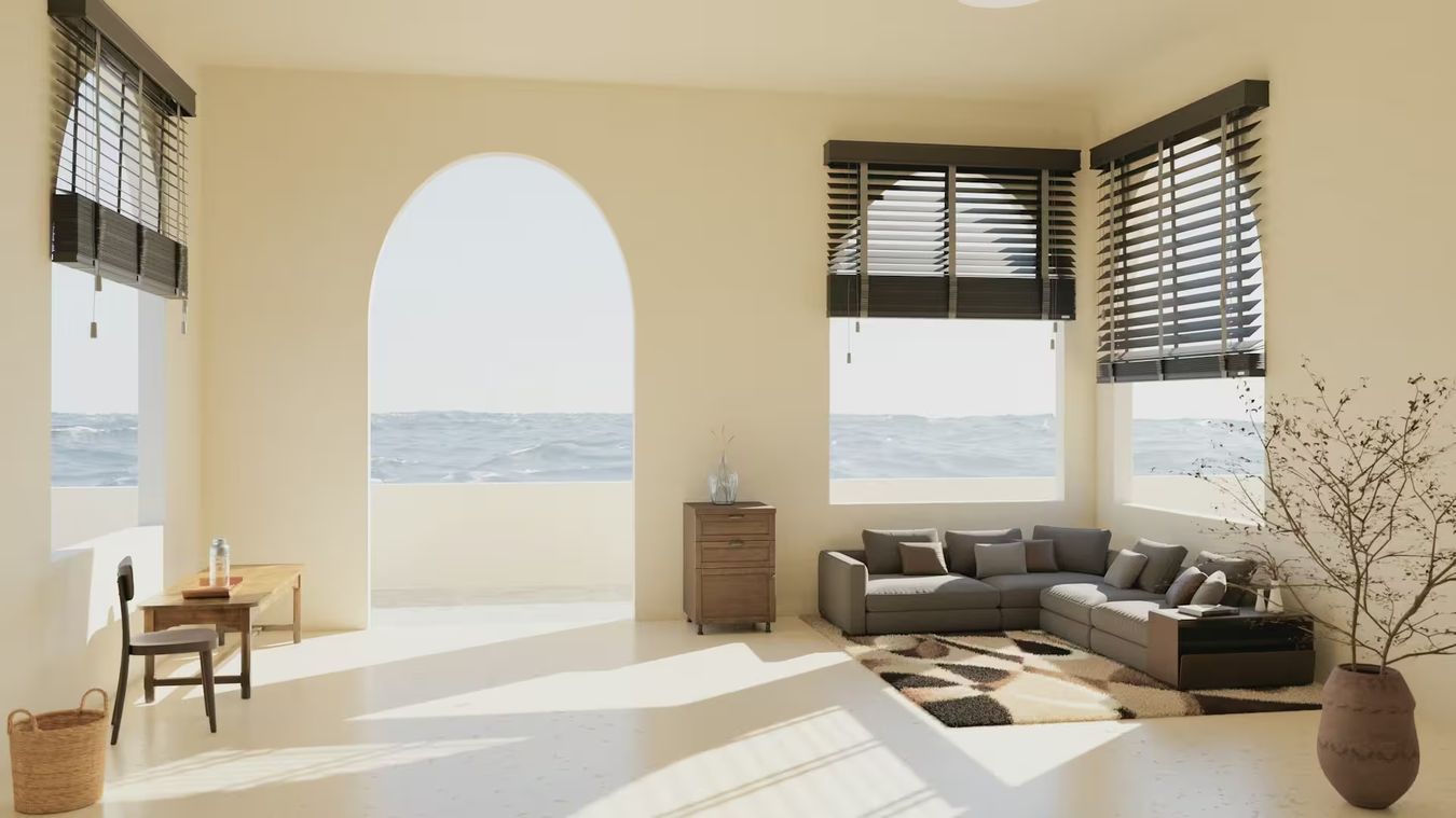 Un séjour ensoleillé aux fenêtres en arcade ouvertes sur la mer, un tapis à motifs sous un canapé d'angle
